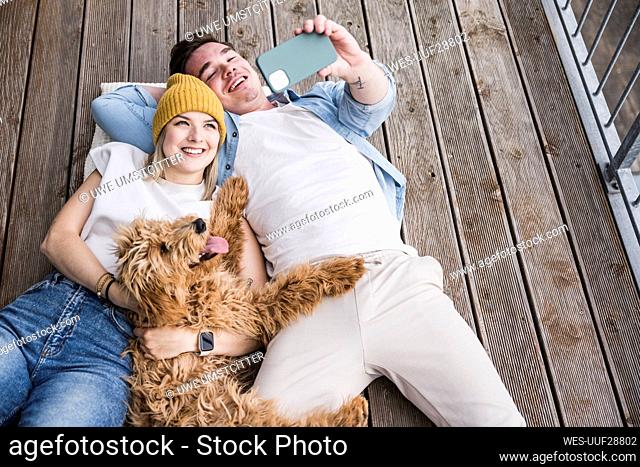 Happy young woman with man taking selfie through smart phone