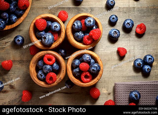 Raspberries and blueberries in wooden bowls