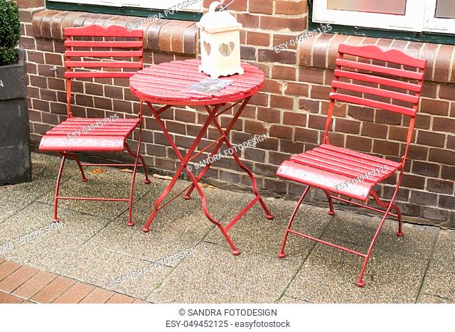 Table and two chairs in red with water drops