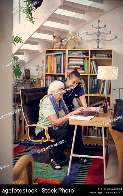 Senior woman and caregiver using laptop