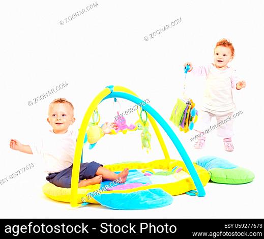 One year old babies (a boy and a girl) enjoy playing with toys. Studio Shot. All toys visible on the photo are officialy property released