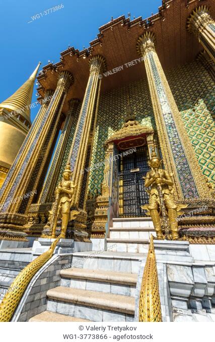 Bangkok, Thailand. View of the golden giant statues guarding massive door to Phra Mondop at Wat Phra Kaew temple in Bangkok, Thailand