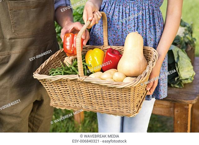 Couple holding basket of vegetables
