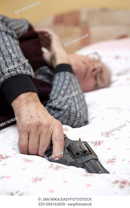 Suicide concept. Closeup of dead senior man holding a gun