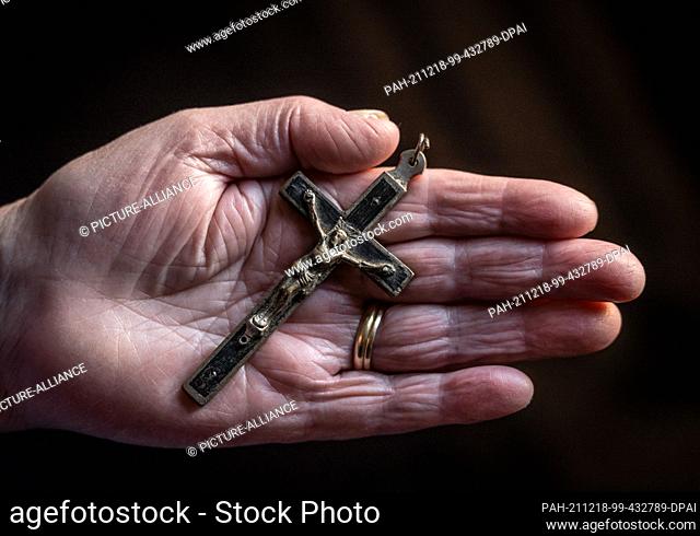 ILLUSTRATION - 17 December 2021, Baden-Wuerttemberg, Rottweil: An old woman holds an old cross in her hand. Photo: Silas Stein/