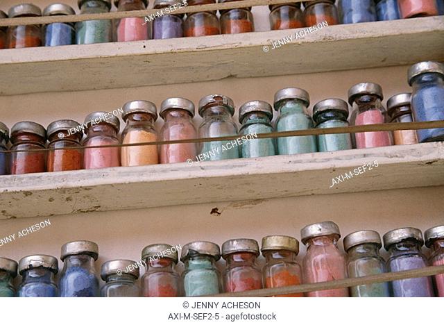 Jars of colored dyes in bottles on shelves