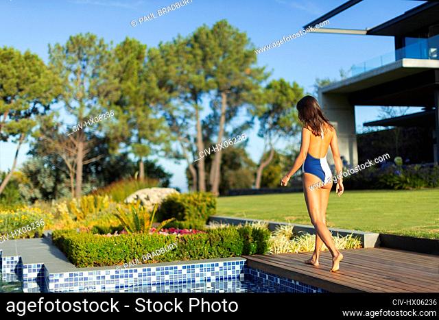 Young woman in bathing suit walking on sunny, luxury patio