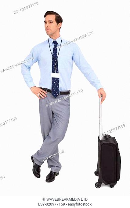 Serious businessman waiting with his suitcase on white background