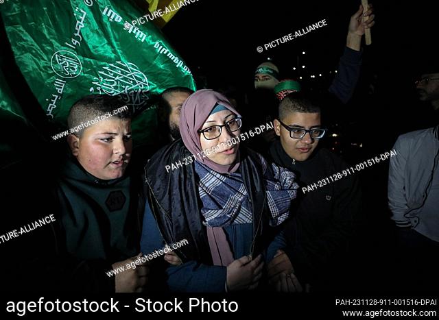 28 November 2023, Palestinian Territories, Ramallah: A Palestinian prisoner (C) is welcomed by friends and family after being released from an Israeli jail