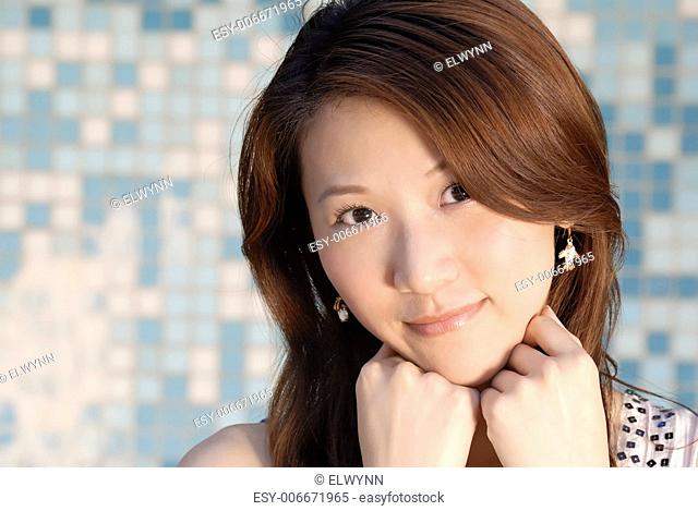 Here is a beautiful Asian lady in front of mosaic and think