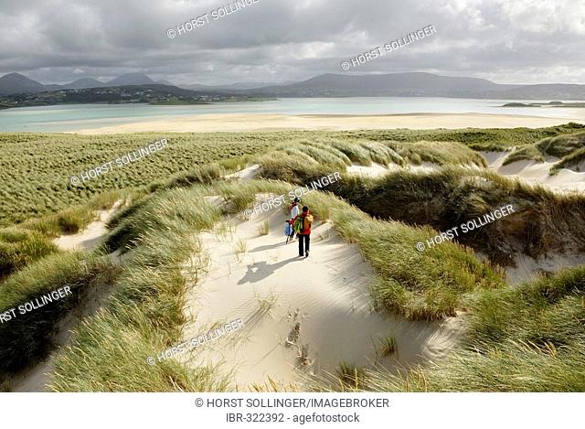 Hiking on sand dune at the shore of Mogarhathy at low tide, Co Donegal Ireland