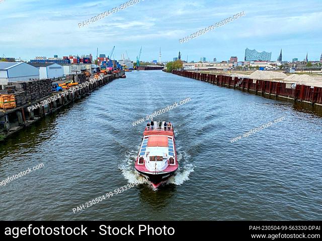 04 May 2023, Hamburg: A barge passes under the Argentina Bridge on a canal in the harbor. In the background the Elbphilharmonie (r-l)