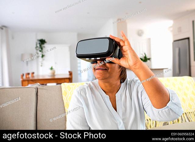 African american elderly woman using wearing virtual reality simulator at home