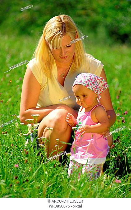 Young mother with daughter in meadow