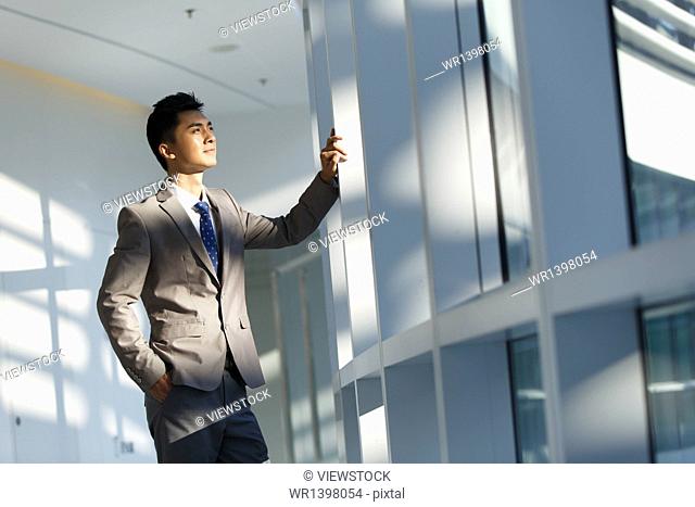 Business man standing in front windows