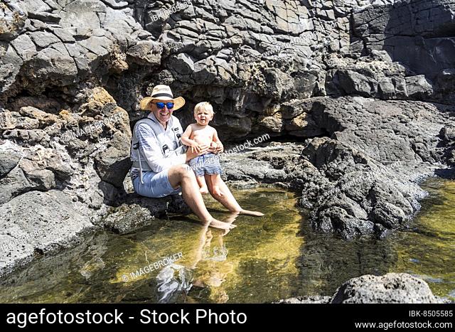 Father with small son enjoying water at Charcones natural pools in Lanzarote, Canary Islands, Spain, Europe