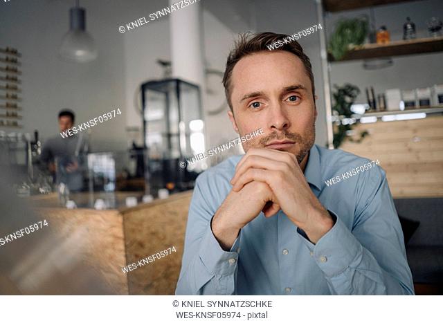 Successful businessman sitting in coffee shop, thinking