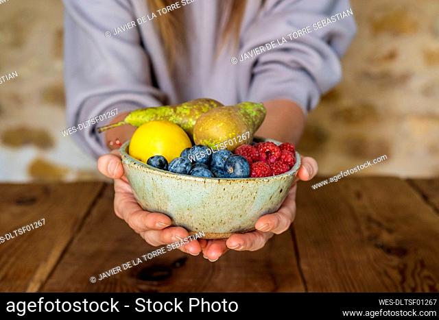Close-up of various fruits in bowl held by female nutritionist at table