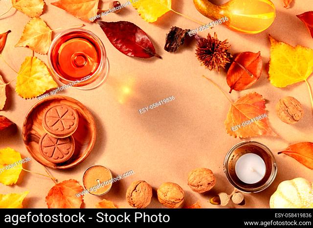 Autumn frame with fall leaves, wine, and cookies, shot from above with a place for text on a brown background