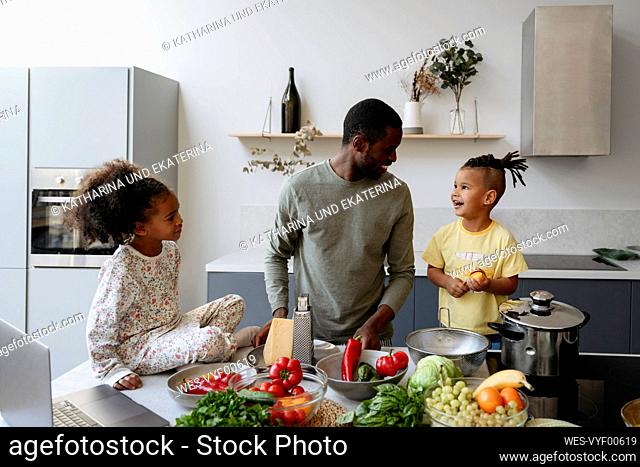 Man talking with son by daughter in kitchen