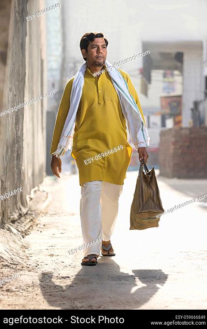 A CONFIDENT RURAL MAN WALKING ON A SUNNY DAY