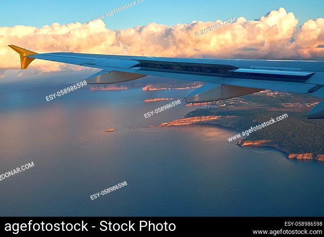 Picturesque scenery to the rocky shoreline, Mediterranean Seascape and fluffy clouds over the land, view from airplane window