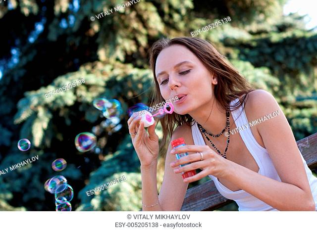 young woman makes soap bubbles