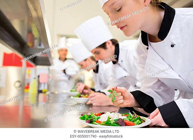 Chef finishing her salad in culinary class in kitchen