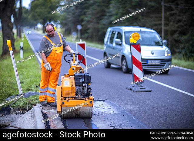 09 September 2020, Mecklenburg-Western Pomerania, Gnoien: Road maintenance workers are working on a bus stop to repair the damage and apply a new road surface