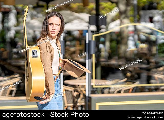 Contemplating female musician with guitar during sunny day