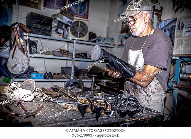 adult male shoemender working at his own workshop