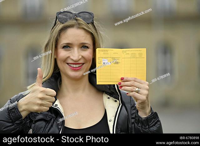 Young woman proudly showing her vaccination certificate after first and second vaccination against Covid-19, Sars-CoV-2, Corona crisis, Stuttgart