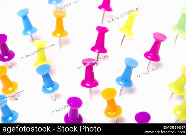View of several scattered pinned colorful push pins isolated on a white background