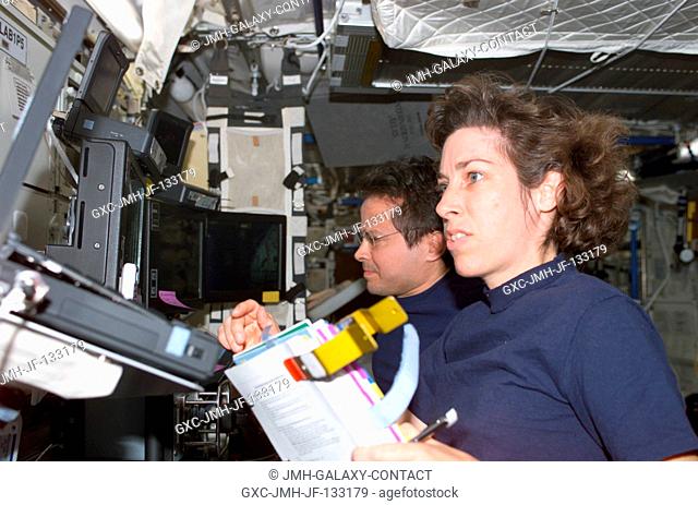 Astronauts Ellen Ochoa (foreground), STS-110 mission specialist, and Daniel W. Bursch, Expedition Four flight engineer, work the controls of the Canadarm2 in...