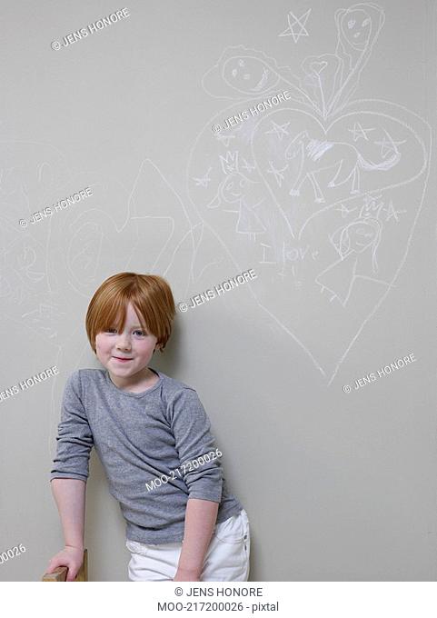 7-8 Year old girl stands below chalk drawing on wall
