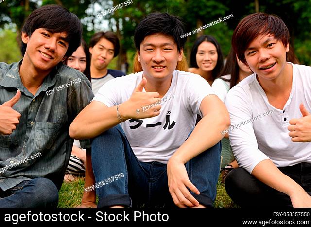 Group of young Asian friends hanging out and relaxing together at the park outdoors