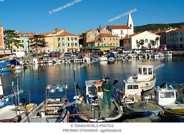 Slovenia, Izola, Town view from the port and fisherman sorting his net