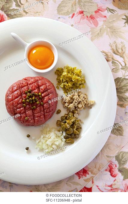 Steak tartare with egg yolk, capers, onions, mushrooms, pickled vegetables and green peppercorns