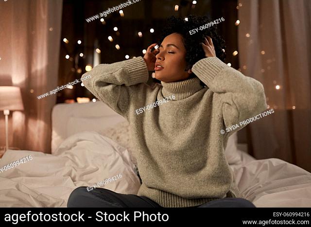 woman in sweater touching her hair in bed at night