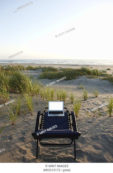 Laptop on deck chair overlooking beach