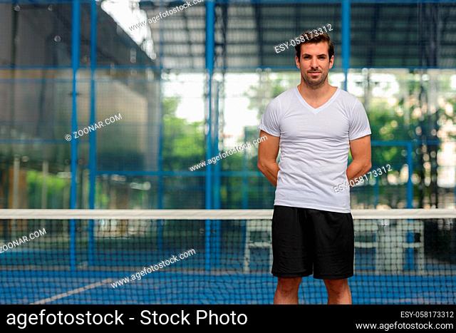 Portrait of young handsome Hispanic man ready to play at the padel court