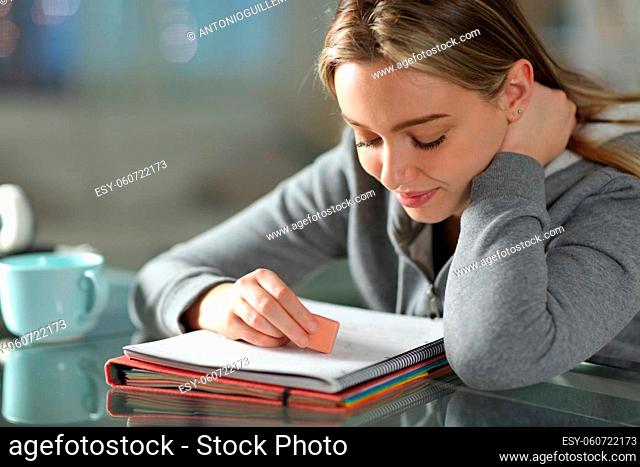 Student erasing text on notebook using eraser at home