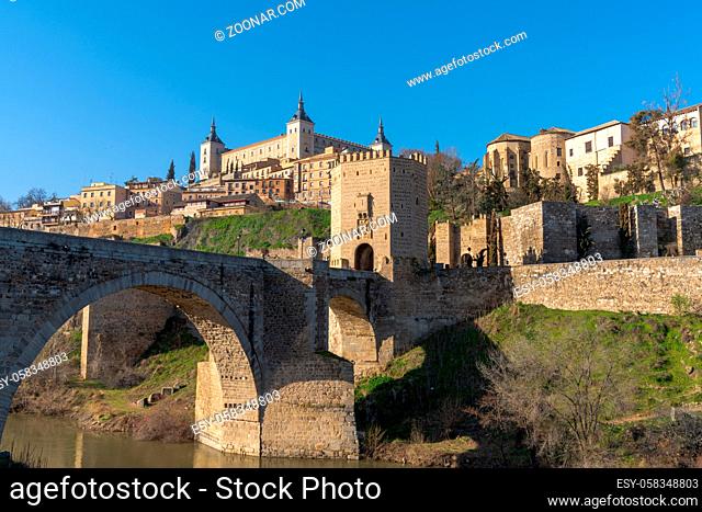 A view of the historic Spanish city of Toledo on the Tagus River with the Roman Bridge in the foreground
