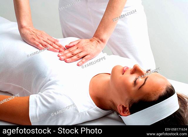 Close up of chiropractor pressing with hands on womans chest at reiki session
