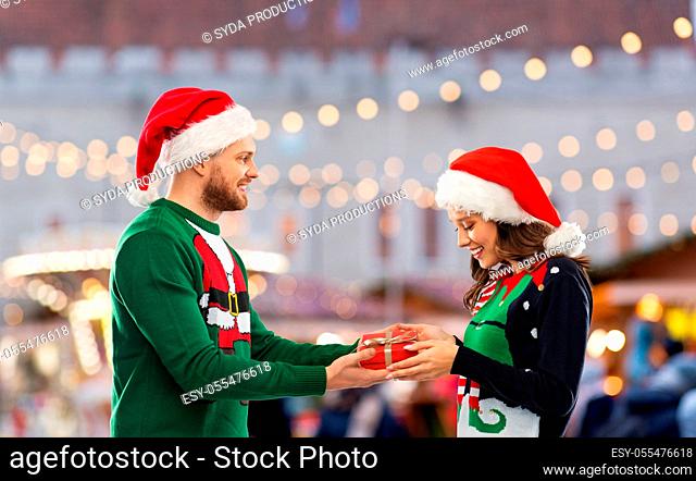 happy couple in christmas sweaters with gift box