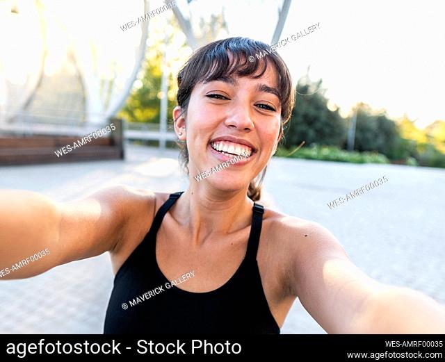 Happy young woman taking selfie at footpath