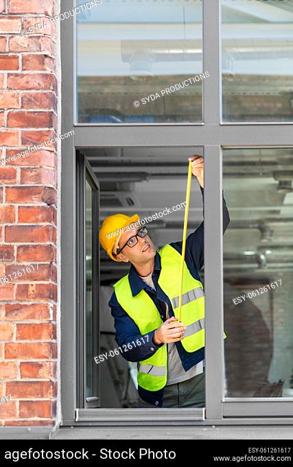 male builder with ruler measuring window