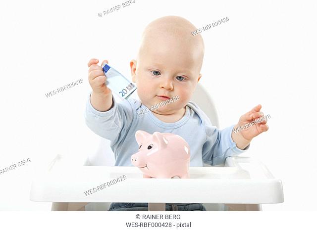 Baby boy 6- 11 Months putting 20 euro note in piggy bank