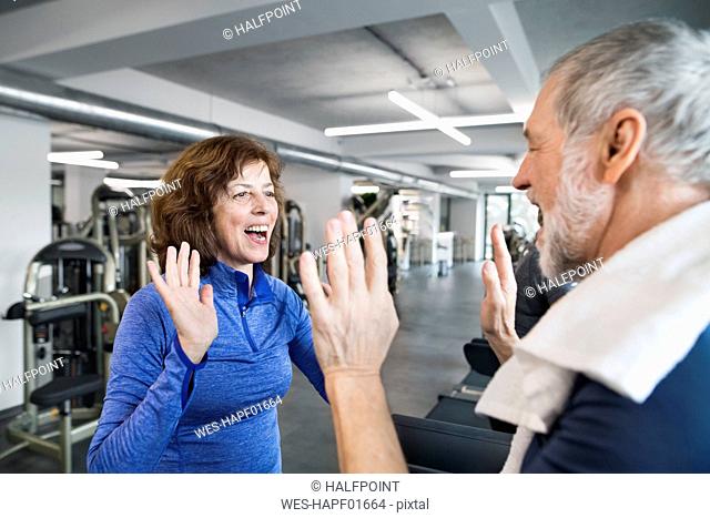 Happy senior man and woman high fiving after working out in gym