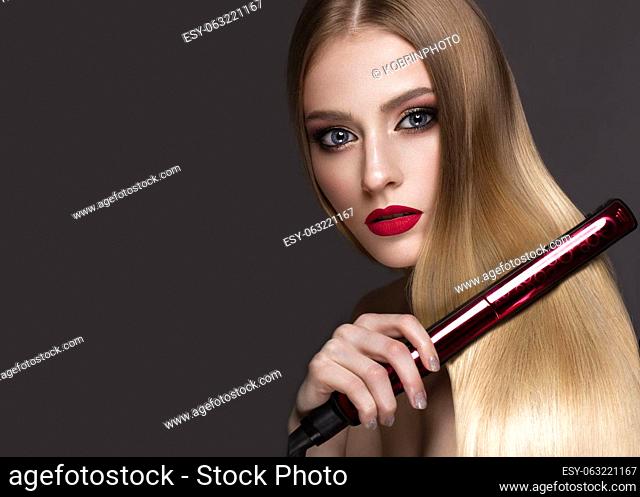 Beautiful blond girl with a perfectly smooth hair, curling, classic make-up and red lips. Beauty face. Picture taken in the studio on a white background